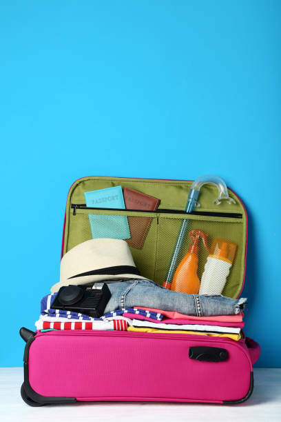 istock Opened suitcase with clothes, camera and sunscreen bottles on wooden table 1041714518