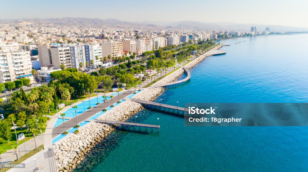 Aerial view of Molos, Limassol, Cyprus Aerial view of Molos Promenade park on the coast of Limassol city centre in Cyprus. Bird's eye view of the jetties, beachfront walk path, palm trees, Mediterranean sea, piers, rocks, urban skyline and port from above. Limassol Stock Photo