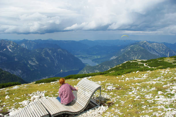istock Red-haired girl on a deckchair looking at a paraglider 1041734346