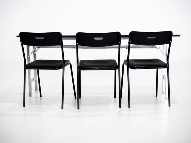 istock Black chairs with white table on white background. Interview place concept 1041740034