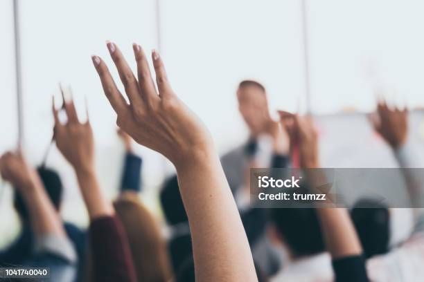 Audience Raising Hands Up While Businessman Is Speaking In Training At The Office Stock Photo - Download Image Now