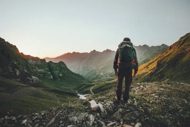 Photo of Man hiking at sunset mountains with heavy backpack Travel Lifestyle wanderlust adventure concept summer vacations outdoor alone into the wild