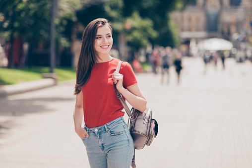 Nice charming attractive cute young cheerful smiling girl outdoors wearing red t-shirt, jeans, walking in park, going to meet her friend