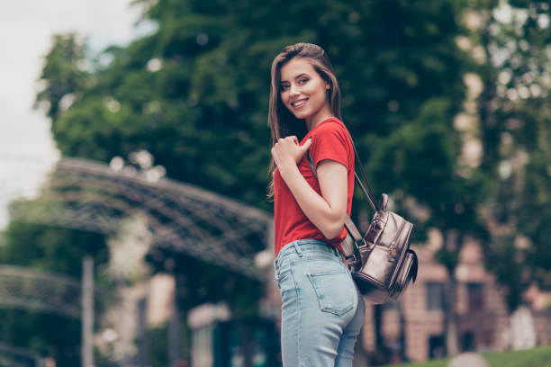 istock Nice charming attractive cute young smiling girl with bag bagpack outdoors, wearing casual red t-shirt and jeans, walking strolling 1041748708