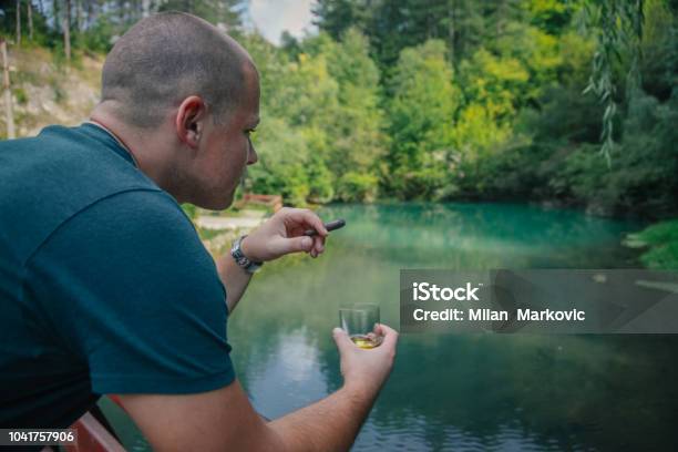 Holding Glass With Whiskey And Smoking Cigar Stock Photo - Download Image Now - 30-34 Years, Adult, Adults Only