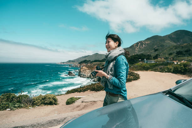 an amateur female photographer taking photos on a cliff surrounded by spectacular scenery