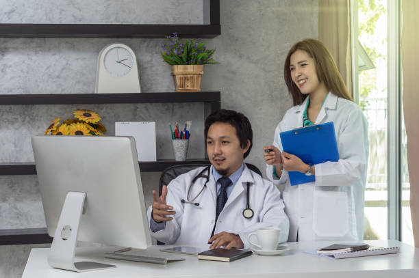 istock Couple of Asian doctors working with colleague which using technology computer in modern office of hospital, physician concept 1041768530