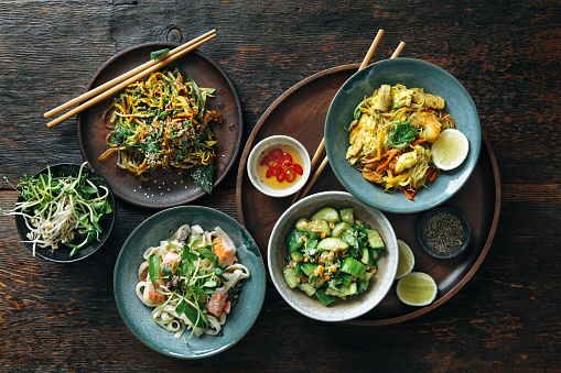 Bowls with Japanese food. Noodles with seafood and vegetables. Udon noodles with salmon. Salad with unagi ell, nori, avocado and tamagoyaki. Salad with cucumbers