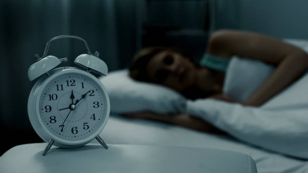 istock Young lady resting in her bed, midnight time shown on alarm clock, night dreams 1041785428