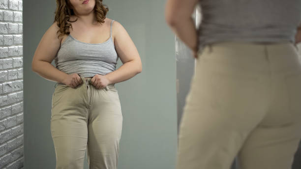 istock Chubby lady trying to get into her pants, overeating result, digestive disorder 1041785778