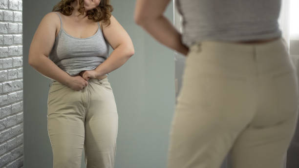 istock Overweight lady having difficulties with getting into her pants, obesity issue 1041785810