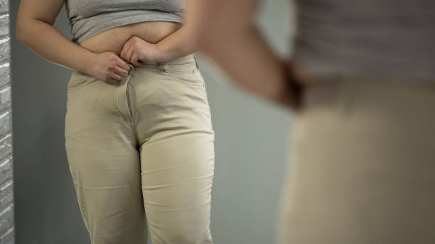istock Obese lady trying to button tight pants, overweight body problem, closeup 1041787174