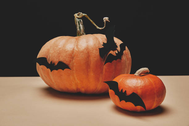 istock two orange pumpkins with paper bats on table, halloween concept 1041790882