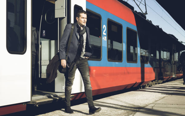Mid adult businessman getting to work by train and arriving on railway station.