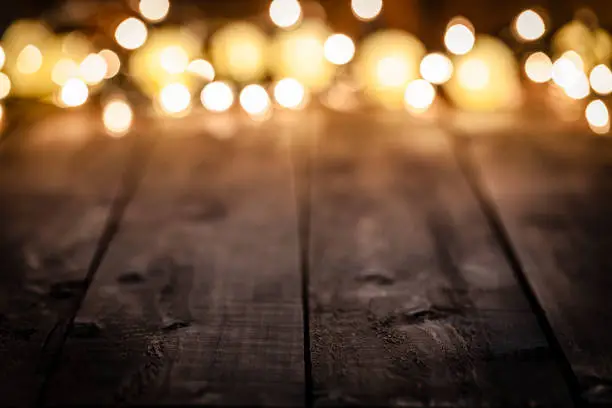 Photo of Empty rustic wooden table with blurred Christmas lights at background