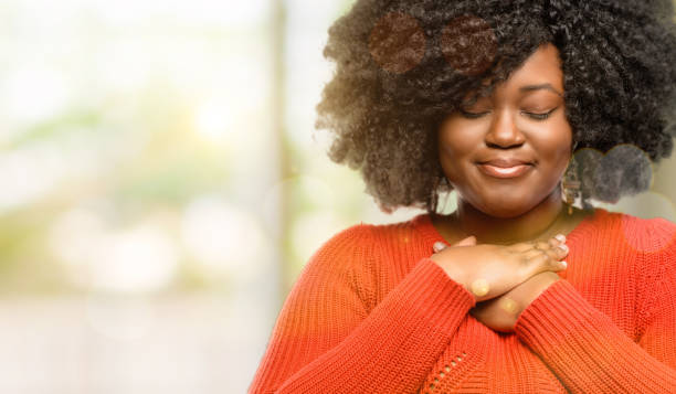 with hands in heart, expressing love and health concept Beautiful african woman with hands in heart, expressing love and health concept, outdoor consoling stock pictures, royalty-free photos & images