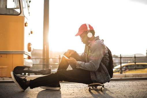 Guy is sitting in the street while listen to the music in the street