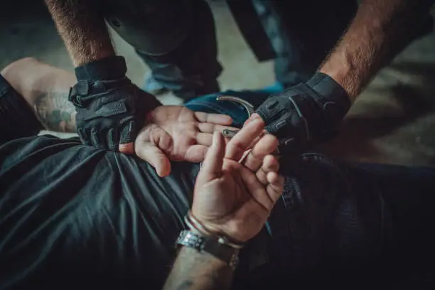 Special police forces man, making an arrest, putting handcuffs on a man/