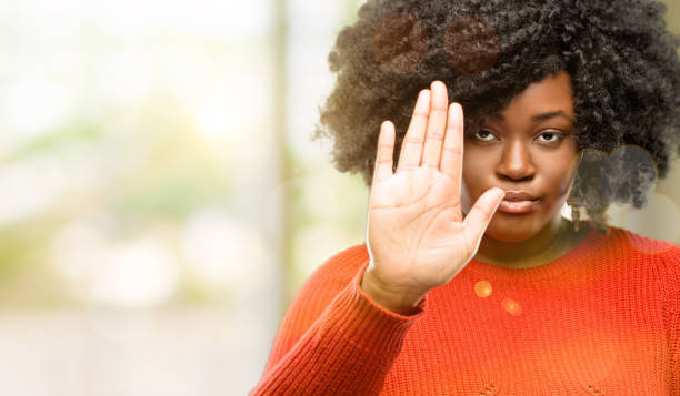 istock annoyed with bad attitude making stop sign with hand, saying no, expressing security, defense or restriction, maybe pushing 1041808432