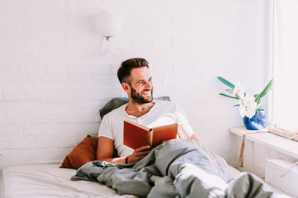 istock Young man reading a book in the bed 1041809890