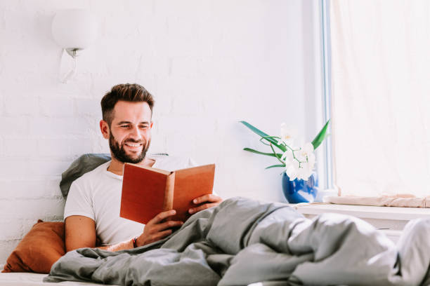 istock Young man reading a book in the bed 1041809902