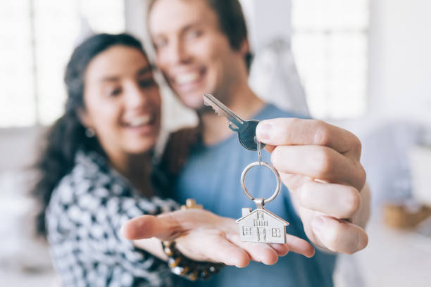 Proprietários de casa alegres casal, segurando uma chave - foto de acervo