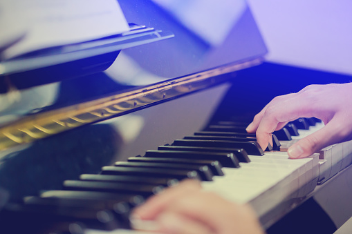 Boy play the piano with selective focus to piano key and hands.