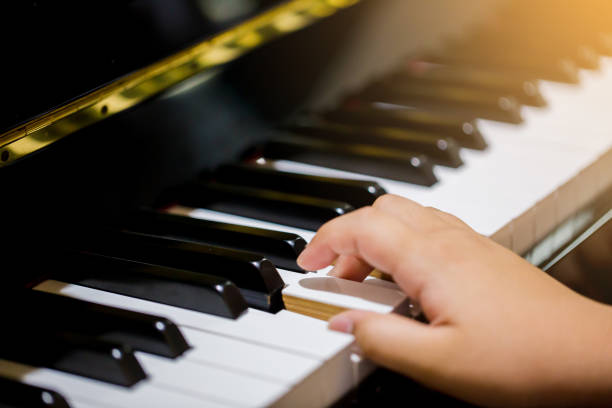 istock Boy play the piano with selective focus to piano key and hands. 1041817378