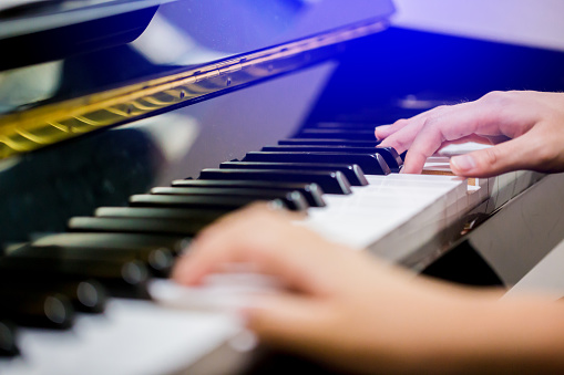 Boy play the piano with selective focus to piano key and hands.