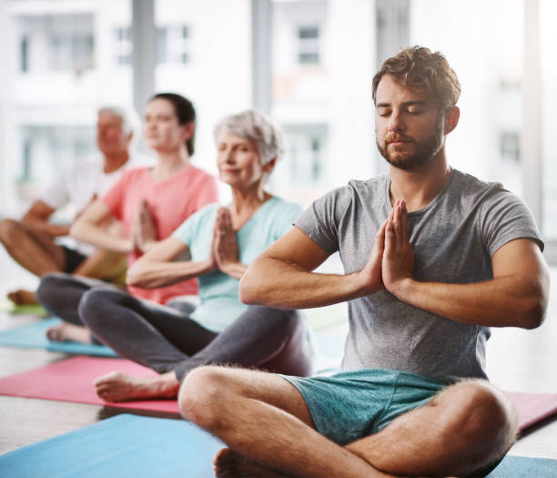 Nothing else matters Cropped shot of a group of people meditating while practicing yoga yoga class photos stock pictures, royalty-free photos & images