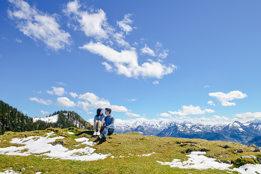 Young Asian couple looking at each other on high mountain, Schafberg mountain (the mountain in movie 'sound of music'), Austria