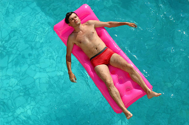 istock Young man floating on a mattress in pool 104184877