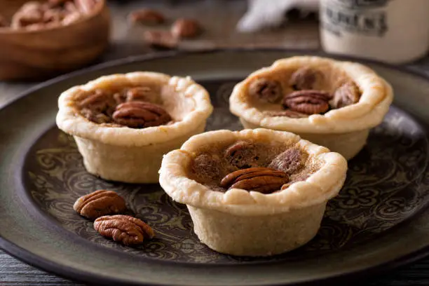 Delicious homemade mini pecan butter tarts on a rustic table top.