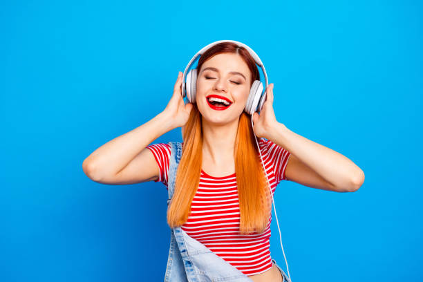 minha faixa favorita! fechar o retrato de foto de positivo otimista com radiante sorriso longo penteado usando fone de ouvido branco menina isolado fundo vívido brilhante - long red hair - fotografias e filmes do acervo