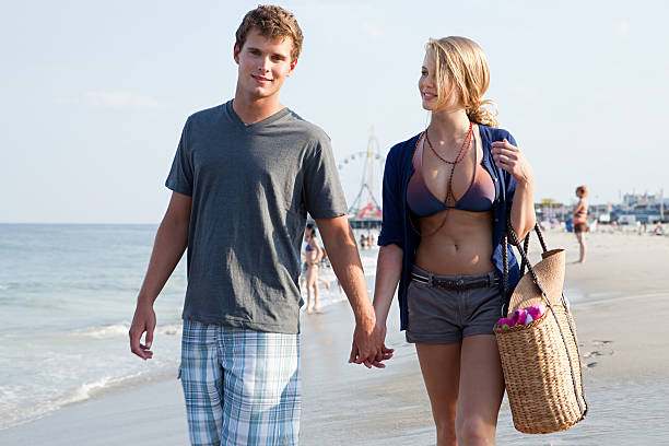 Teenage couple walking hand in hand on beach Dating girl stock pictures, royalty-free photos & images