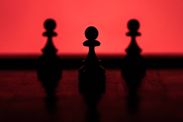 Pawns chess pieces silhouettes on a red background with the center pawn standing out