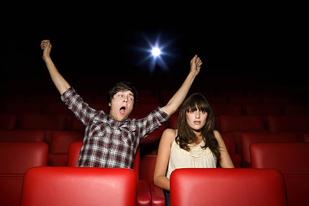 Teenage boy pretending to yawn in the movie theater  couple on bad date stock pictures, royalty-free photos & images