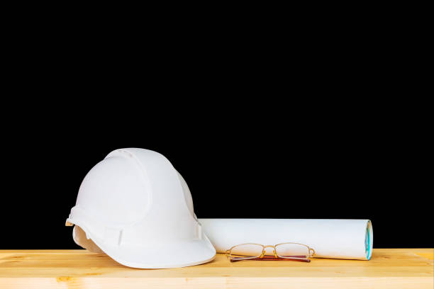 istock helmet plastic white and glasses with paper roll plan blueprint. hat safety equipment working of engineering concept construction on Wooden floor isolated black background clipping path 1041891690