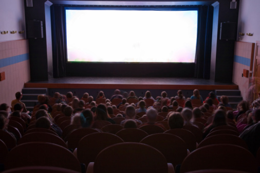 People in cinema auditorium sitting in line of chairs are watching projection screen with movie performance. Ready for adding your own picture.