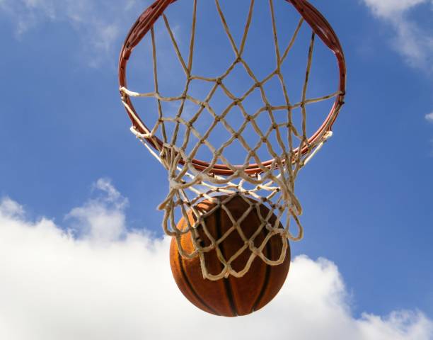 istock Basketball Going Through A Net Against The Cloudy Sky 1041893610