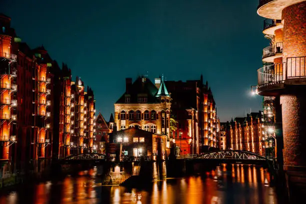 Photo of Hamburg, Germany. View of Wandrahmsfleet at dusk in light illumination. Located in Warehouse District -Speicherstadt Landmark of HafenCity quarter. Most visited touristic famous place