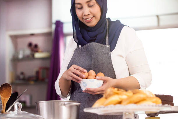 Muslim female baker preparing to bake a cake Female baker holding eggs and preparing to bake a cake. small business malaysia stock pictures, royalty-free photos & images