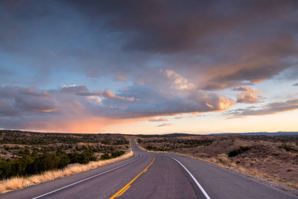 Desert highway curving into a dramatic sunset under beautiful clouds