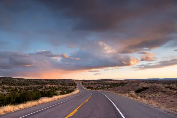 Photo of Desert highway curving into a dramatic sunset under beautiful clouds