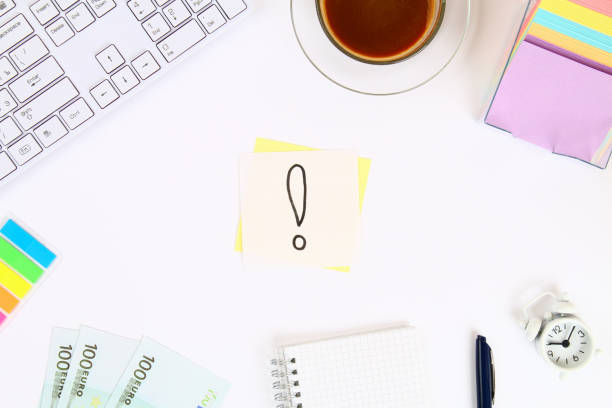 istock An exclamation point on the sticker is a note on a white desktop next to a coffee mug and a keyboard. Top view, flat layout. 1041939180