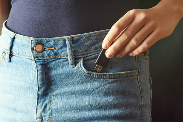 istock Young woman pushing a flash disk into a jeans pocket. Holds Flash Drive in hand. Dark background. 1041943152