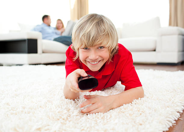 istock Happy boy holding a remote lying on the floor 104194939