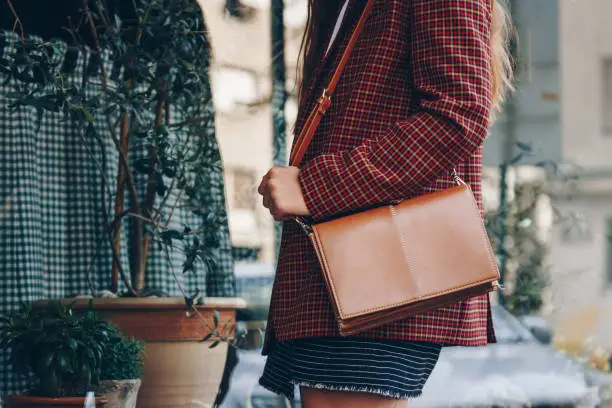 Photo of attractive woman wearing a  mini skirt, check plaid blazer and a lether brown tote bag. fashion outfit perfect for autumn. style of 2018 autumn.