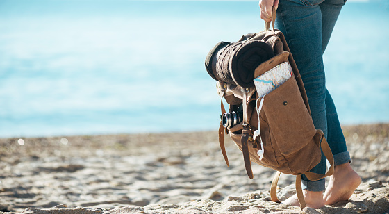 Soporte de viajero de mujer en la playa de arena y sostiene la mochila. Concepto de viaje. photo
