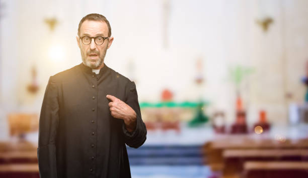 istock Priest religion man happy and surprised cheering expressing wow gesture, pointing with finger 1041972362